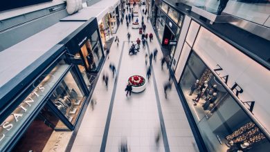 Shopping movimentado, com consumidores circulando diante de lojas modernas.