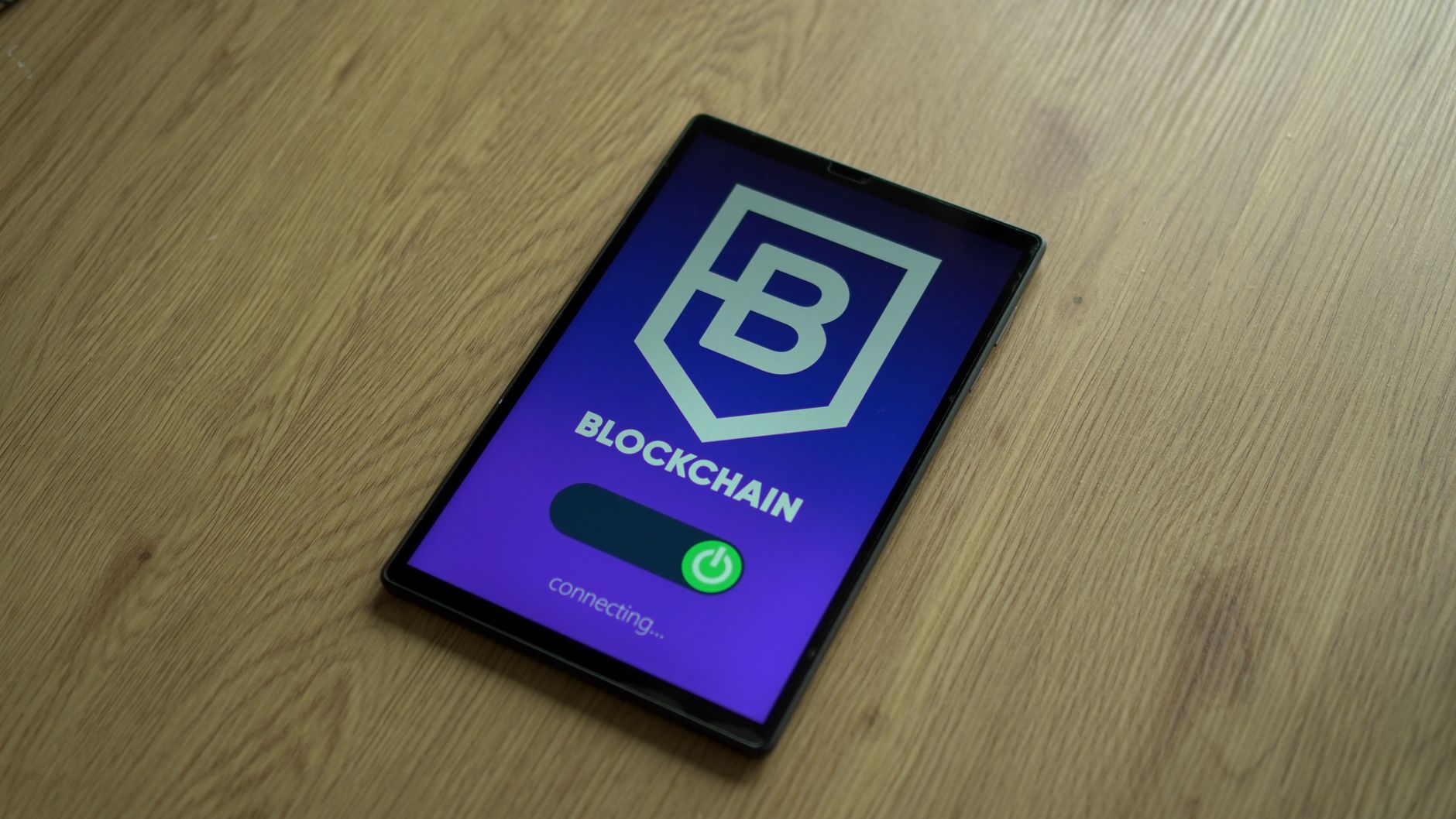 Tablet exibe um conceito de blockchain sobre uma superfície de madeira.
